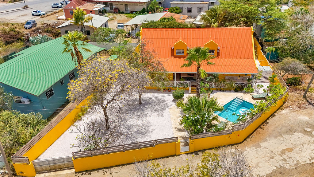 Aerial view of the orange-roofed villa and pool from the street side