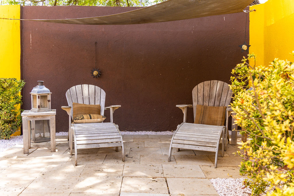 Shaded Adirondack loungers under the sail shade