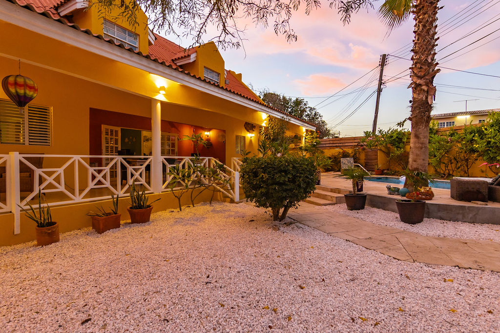 Warm veranda lights and pink sunset sky over the garden path