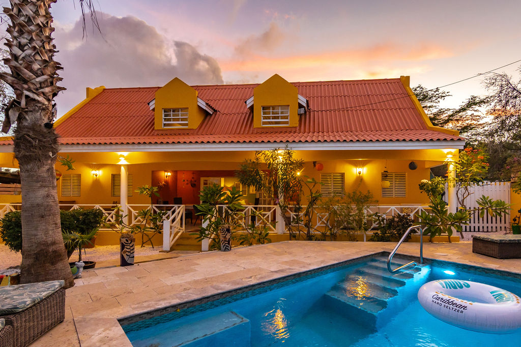 Pool glowing turquoise with the lit villa at sunset