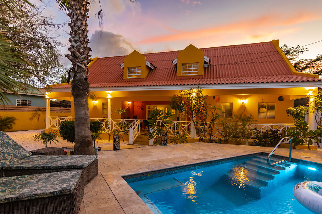 Sunset view of the villa, palm and travertine pool deck