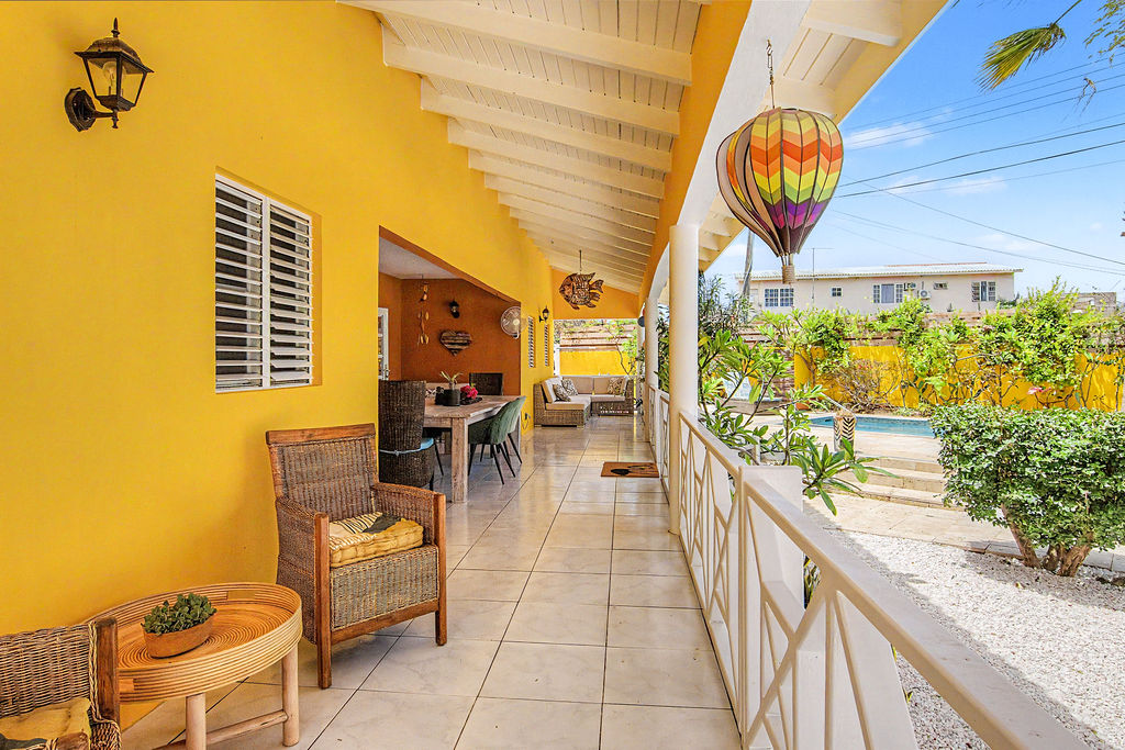 Sunny yellow veranda with wicker seating
