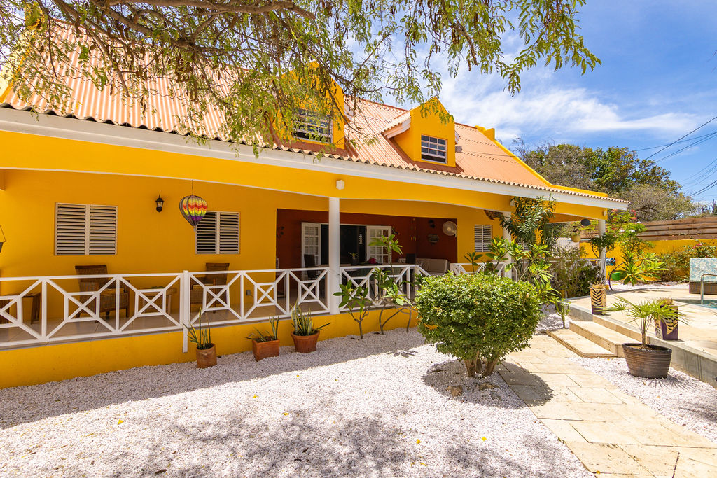 Covered veranda with white railings and tropical garden